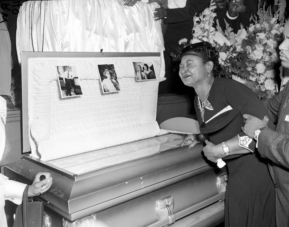 Mamie Bradly leaning on her son's casket which is currently on exhibit at the National Museum of African American History